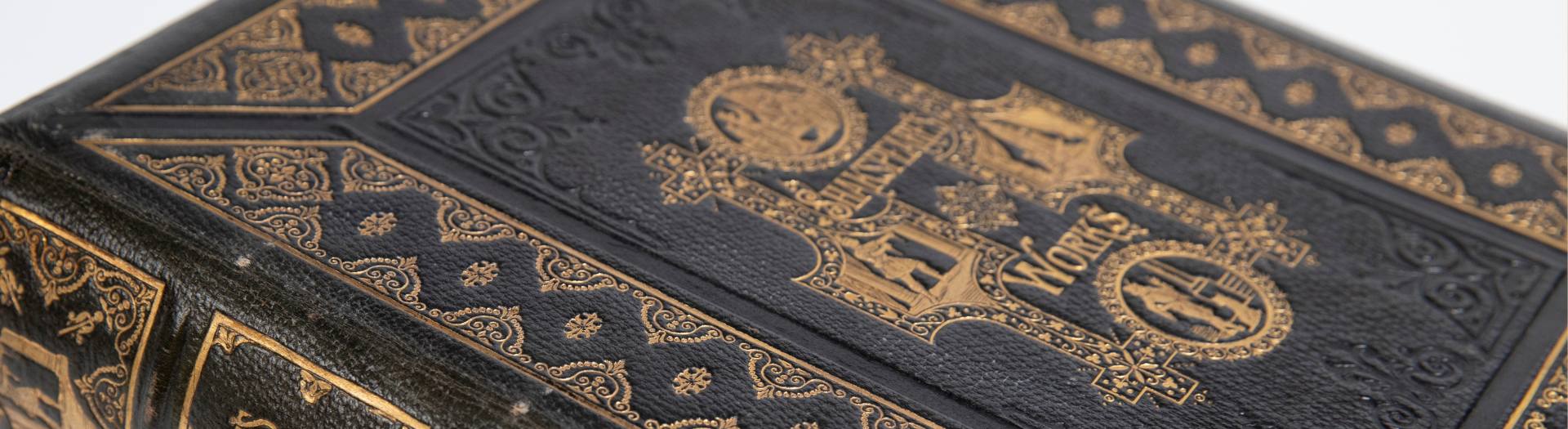 Cover of old, hardcover black book with gold detail. Ornate text on the cover reads 'Shakespeare's Works' 