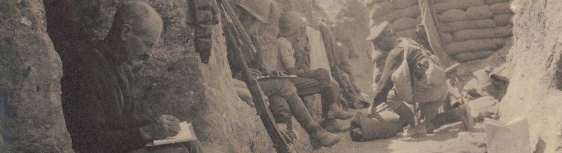 Sepia toned photo of soldiers sitting in a trench writing letters