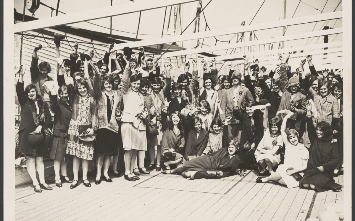 Black and white photo of British migrant women waving on the deck of a ship