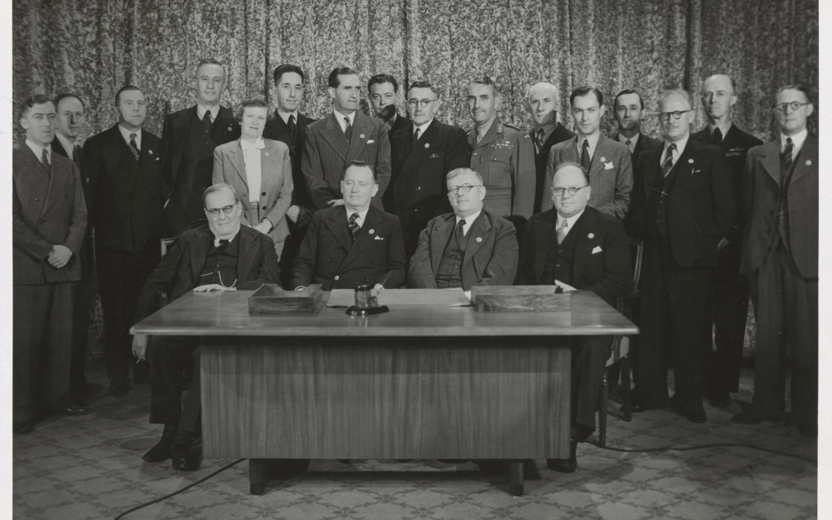 black and white photograph of a group of men gathered around a desk