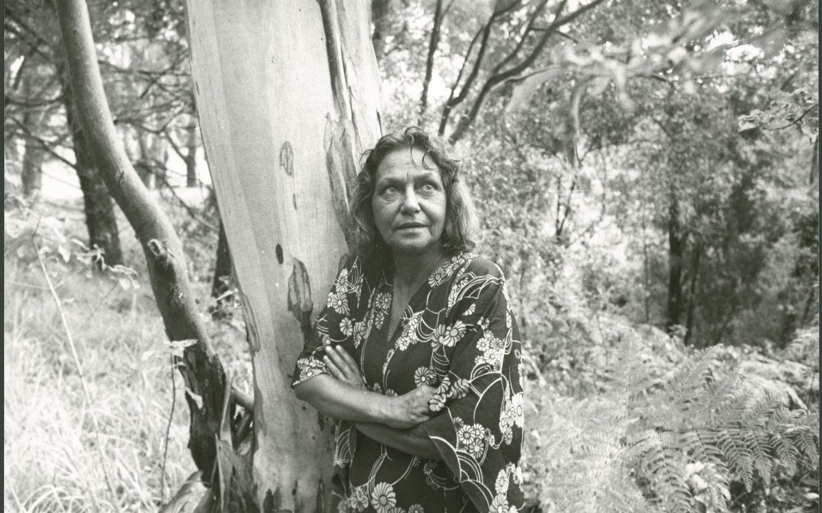 black and white photograph of an Aboriginal woman leaning against a tree