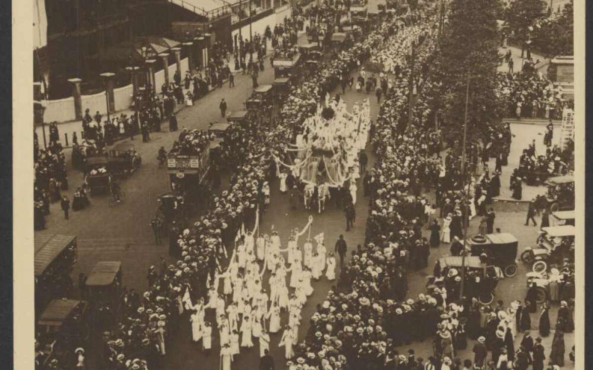 A sepia photograph showing a large group of people marching down a city street