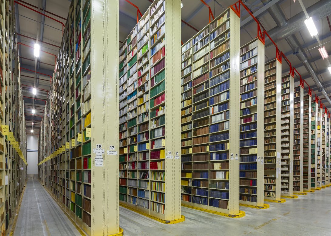Rows of very tall, large bookshelves (stacks) in a warehouse