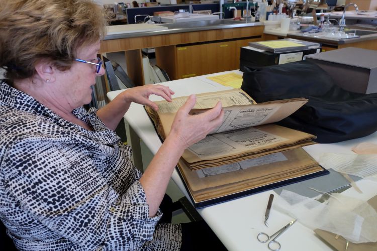Conservator turning pages of a theatre scrapbook