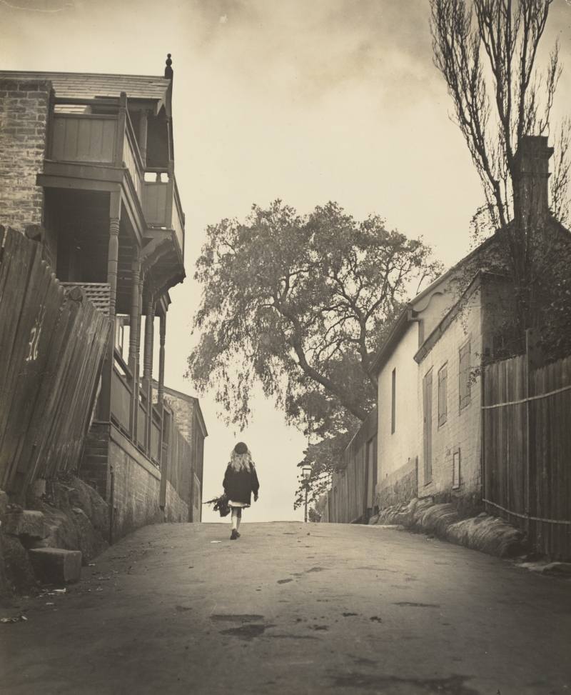 Girl walking up a street in 1910