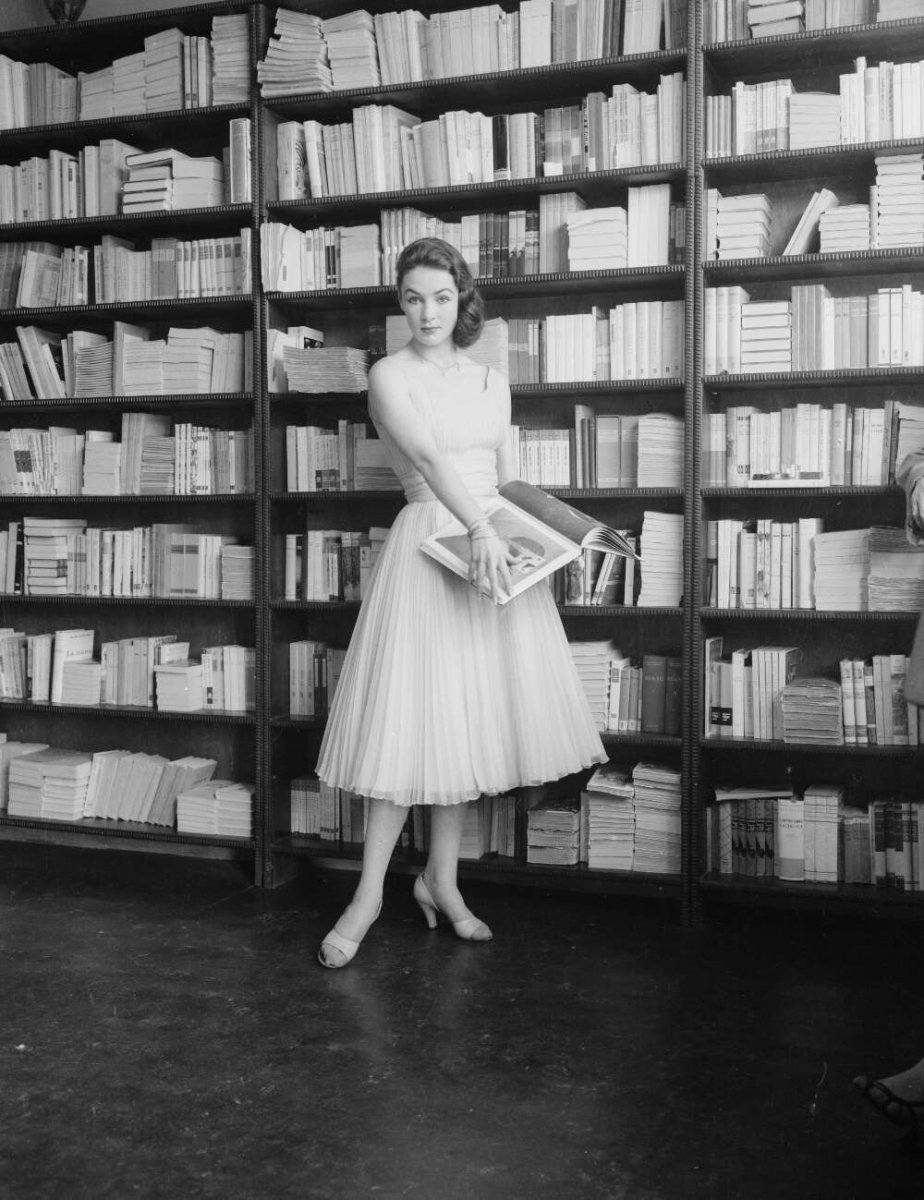 A model holding a book in front of a book case