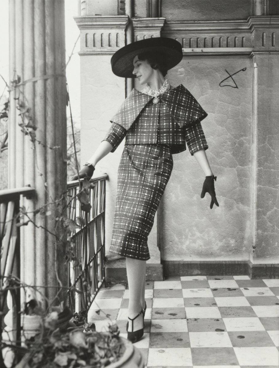 A model in a dress and hat standing on a balcony, approximately 1968
