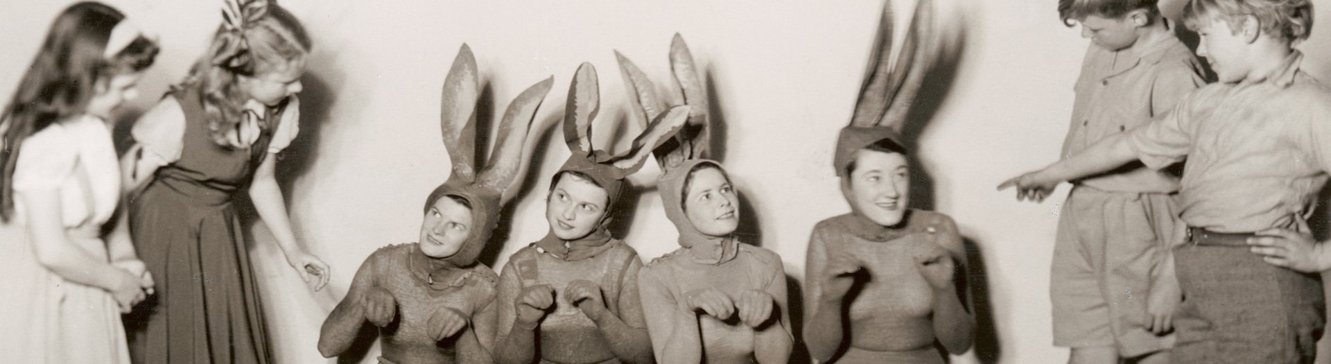 Children interacting with four women dressed as easter bunnies