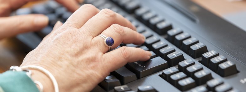 Close-up of hands typing on a black computer keyboard