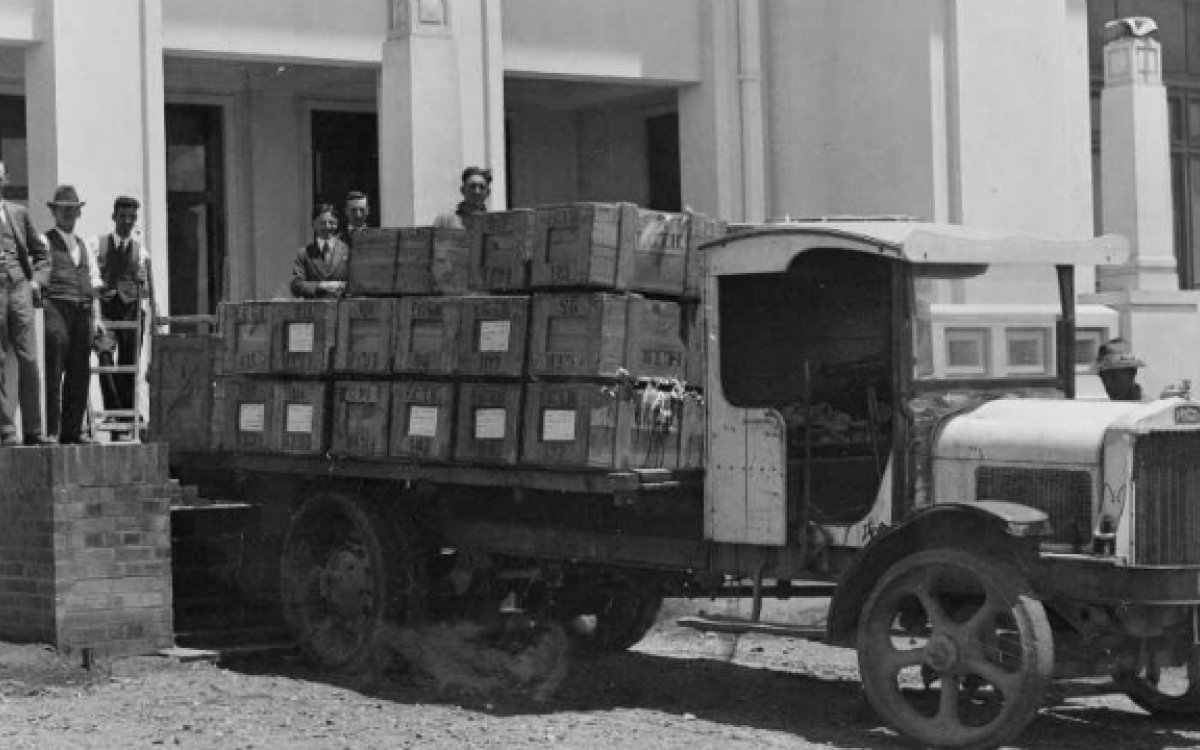 Six men standing around a truck loaded with crates of books outside Old Parliament House