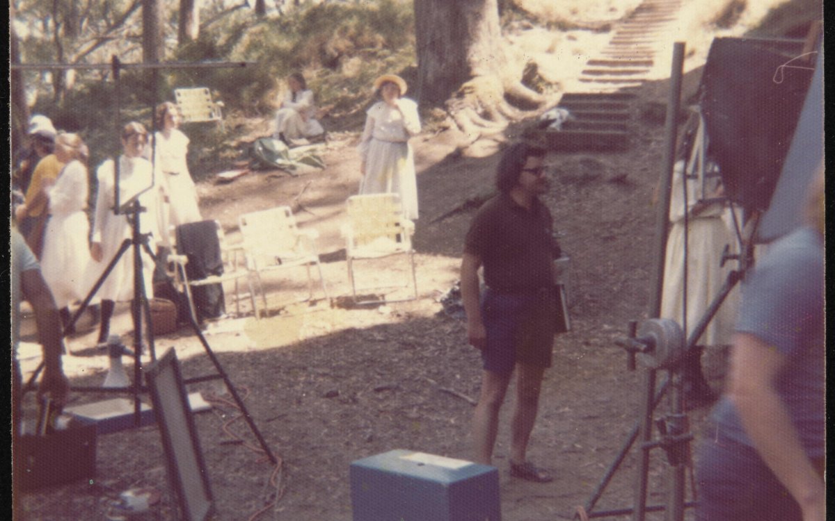 filming equipment in bushland with group of girls in Georgian dress inbackground