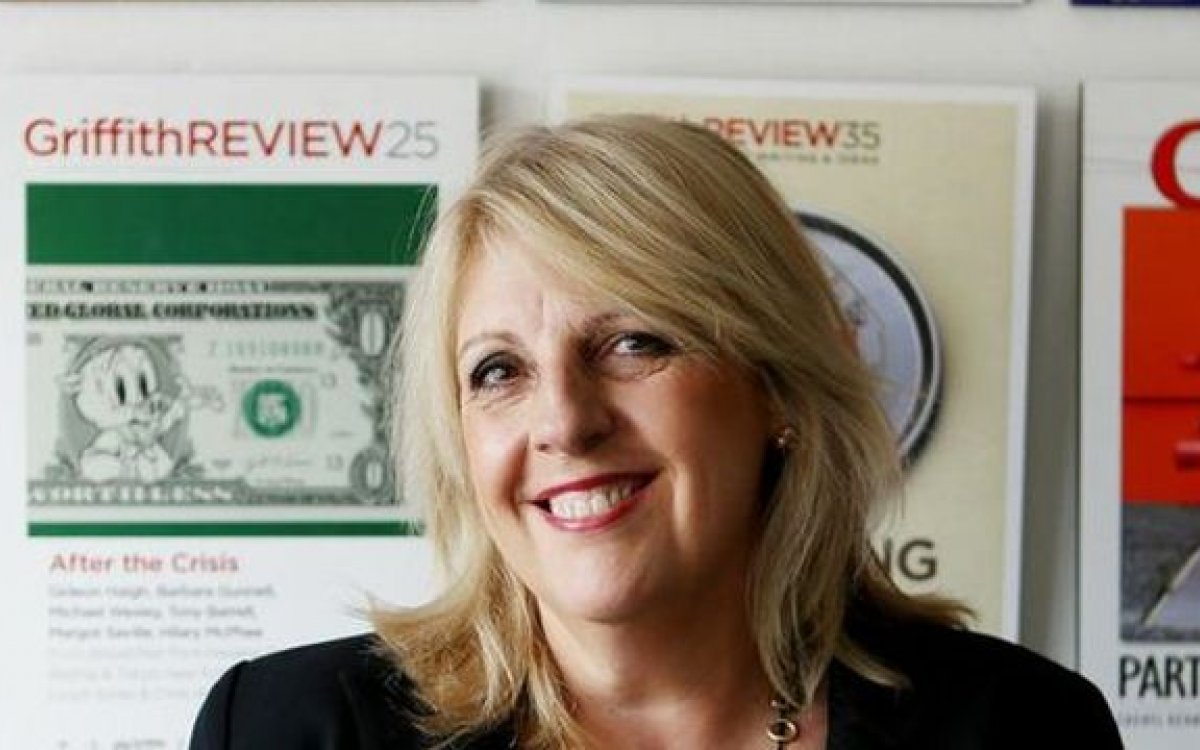 A photo of a woman with blonde hair and magazine covers in the background.
