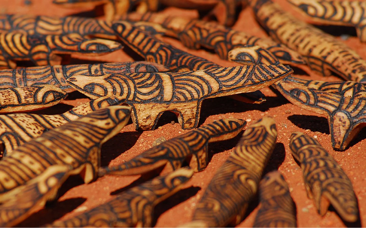 Carved wooden objects arranged on red sand