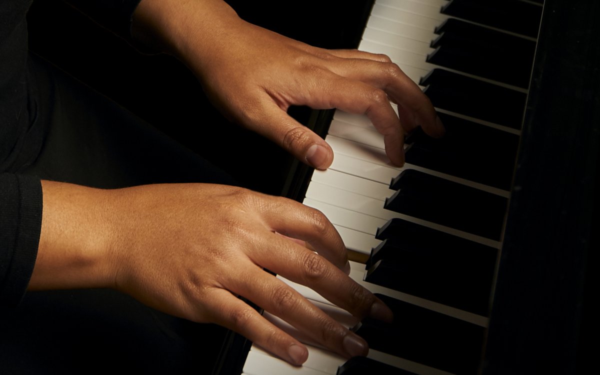 Dr Tonya Lemoh's hands on the keys of a piano.