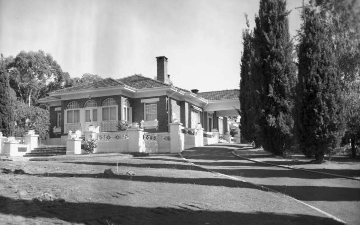Black and white photograph of a house set in lush gardens