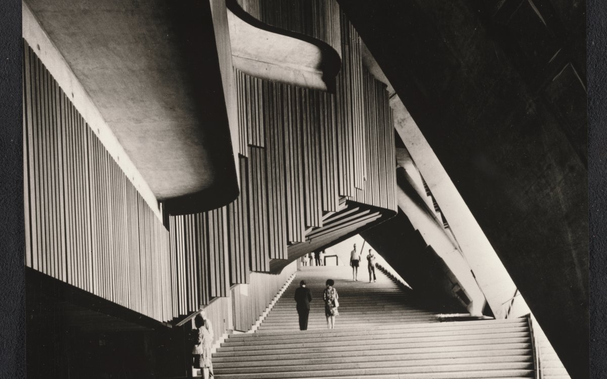 A sepia photograph of the interior of the Sydney Opera House. The architecture is a series of geometric patterns at opposing angles and directions.