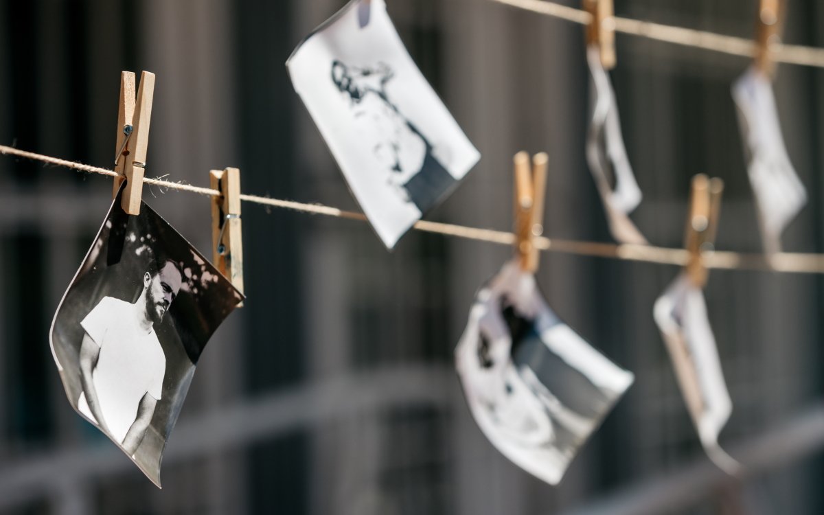 Black and white photographs hanging on two rows of twine, being held up by wooden pegs.