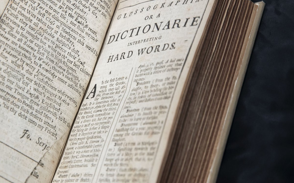 An old rare dictionary opened to a page with lots of text. 