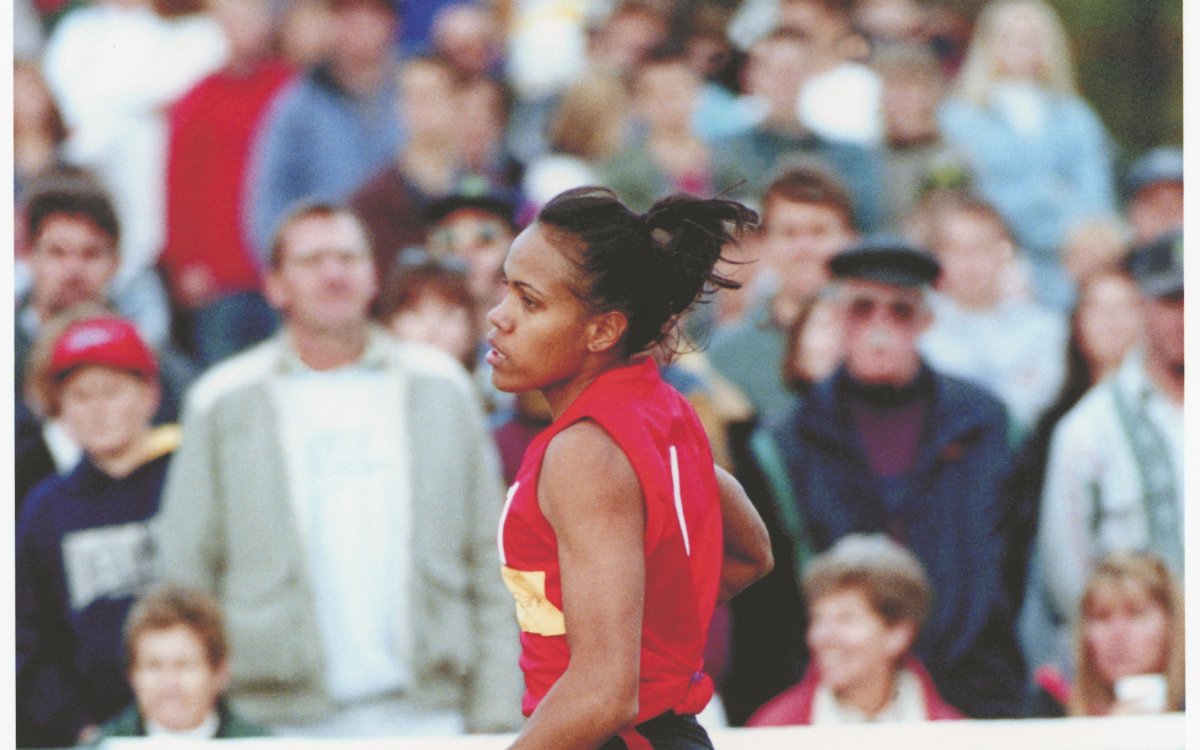 Photo of Cathy Freeman running in front of a crowd at a sport stadium