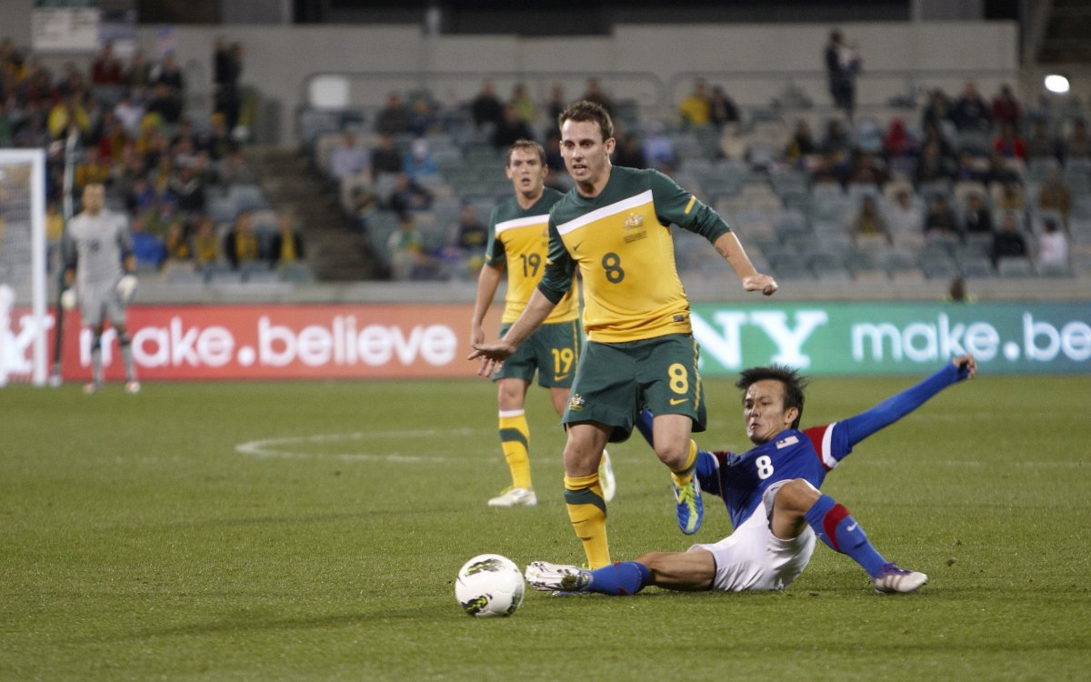 Photo of a Socceroos player being tackled by a Malaysian player