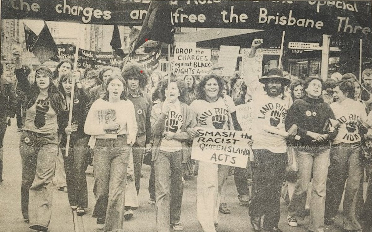 A sepia image of a group of people marching in a protest for Australian First Nations land rights