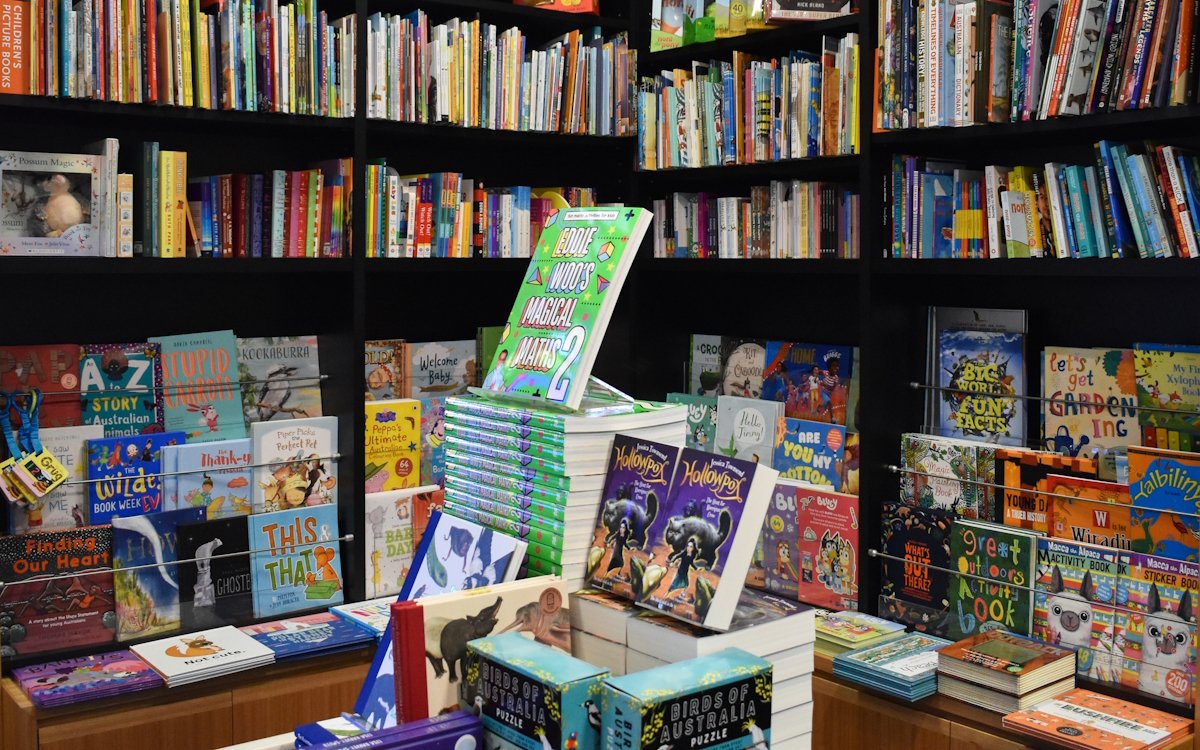 Lots of children's books on bookshelves and displayed on a table.