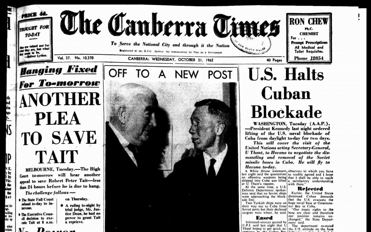 The front page of The Canberra Times newspaper. Several headlines scatter the page. One reads "U.S. Halts Cuban Blockade". There is a black and white photograph of Prime Minister Menzies shaking hands with Donald Cameron, High Commissioner to New Zealand