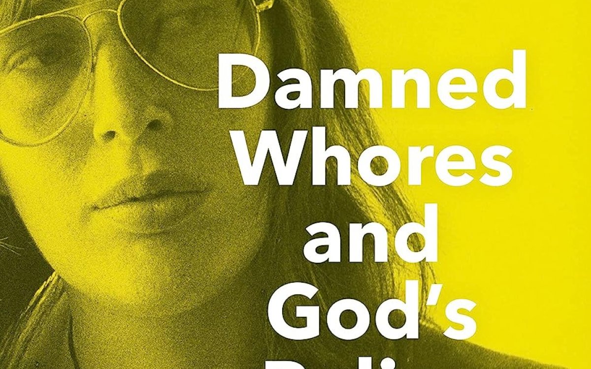The front cover of a book. It is yellow and grey. A woman wearing large glasses looks off camera. The title of the book reads "DAMNED WHORES AND GOD'S POLICE - ANNE SUMMERS"