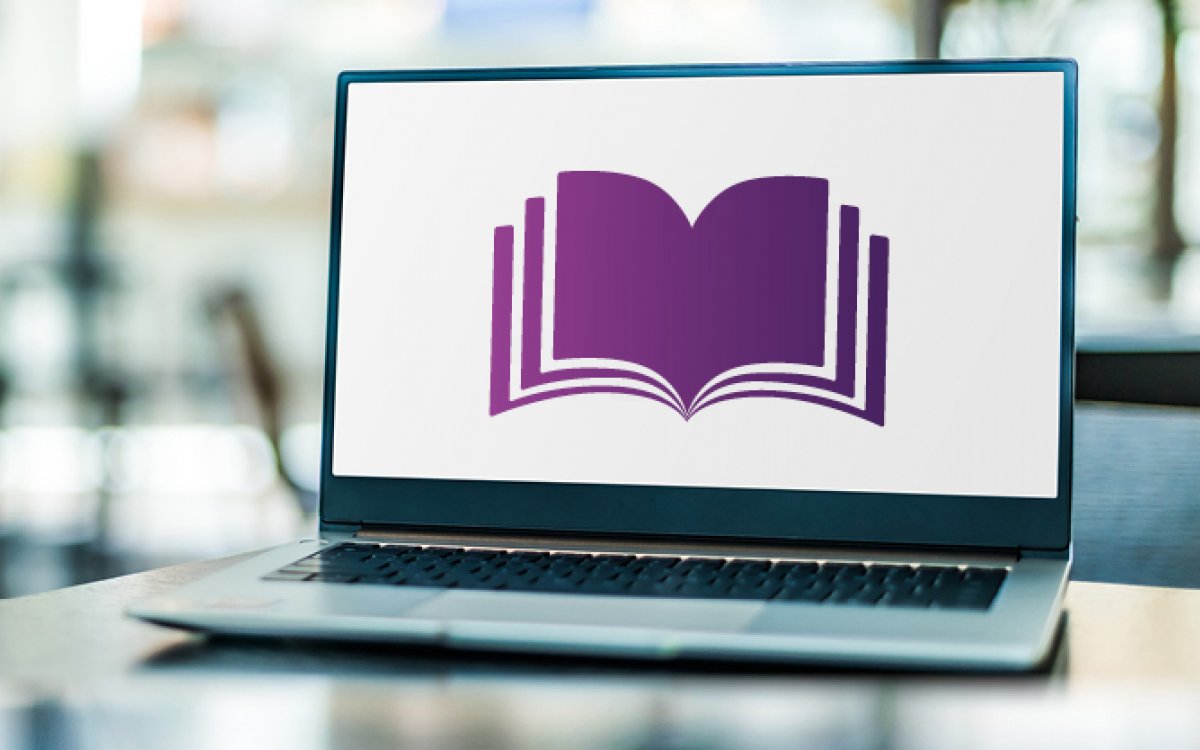 A laptop sitting on a desk with a stylised purple book on the screen.
