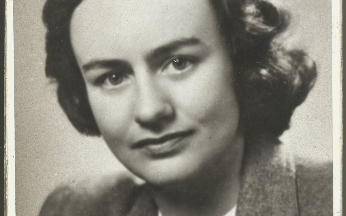 A black and white portrait photo of a young woman with brown hair in a 1940's hairstyle, wearing a wool suit jacket over a white lace shirt.