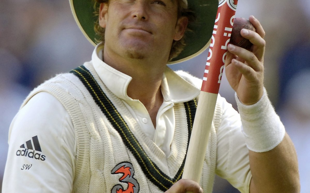 Photo of Shane Warne holding a cricket stump and ball