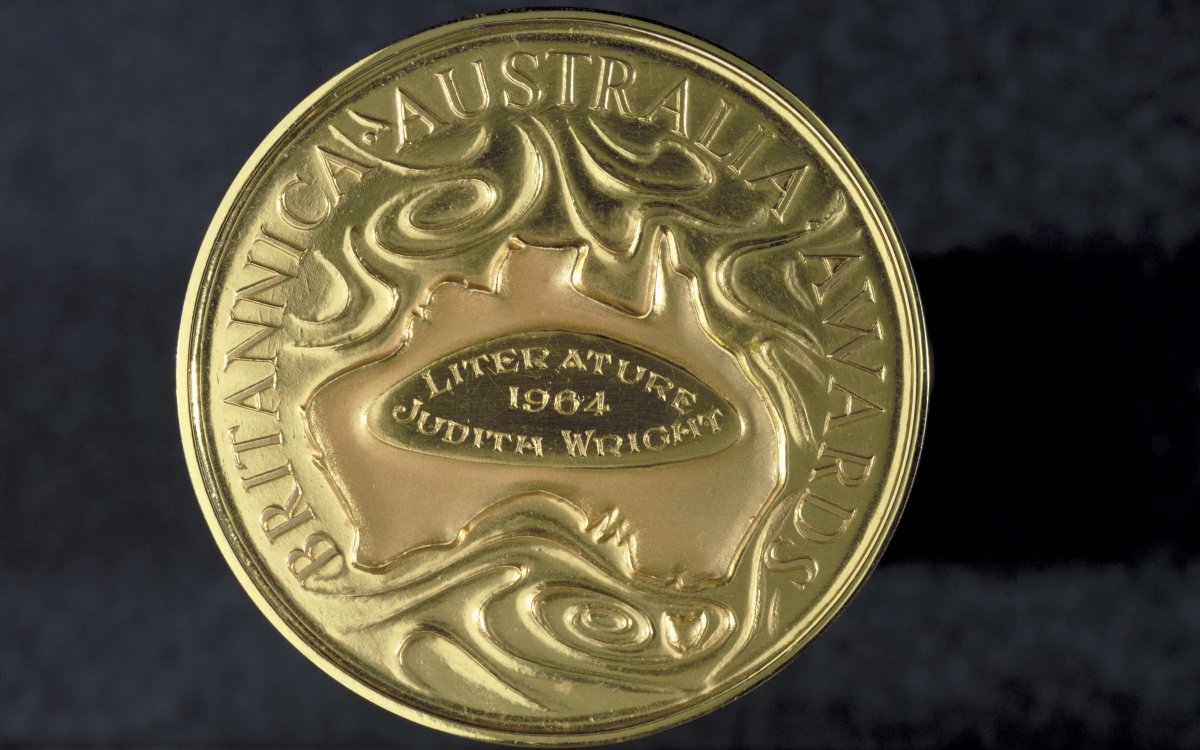 A photo of a gold medal showing a map of Australia surrounded by the words Britannica Australia Awards. In the middle of the map of Australia are the engraved words 'Literature, 1964, Judith Wright'.