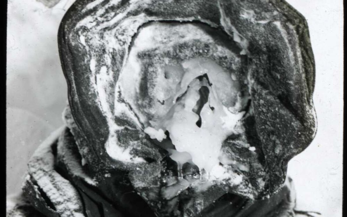 A black and white photo of a person with a hooded head and ice where the face should be.