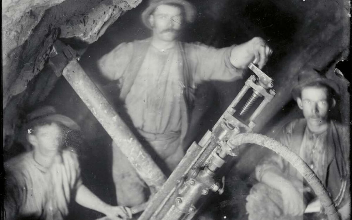 black and white photograph of three miners with an early pneumatic drill