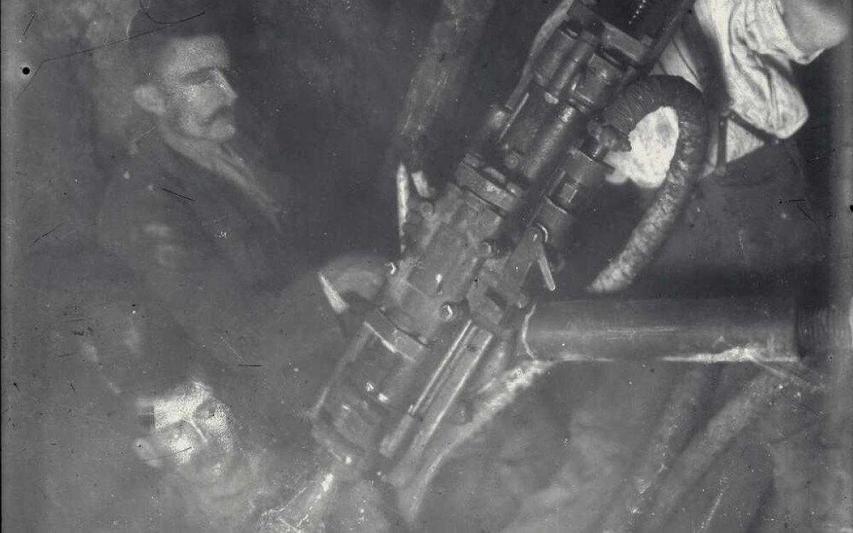 black and white photograph of three miners with early pneumatic hammer drill