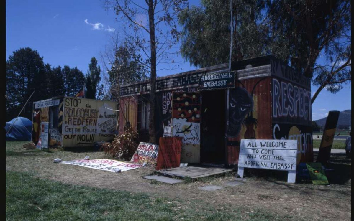A photo of two tent decorated with painted words and Aboriginal art and a sign saying 'All welcome'.