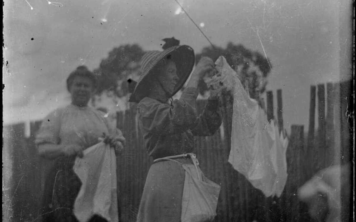 black and white photograph of two women hanging washing on a clothes line