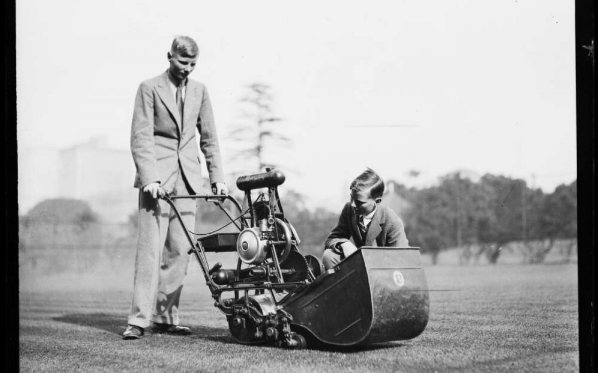 black and white photograph of two young men examining a lawn mower