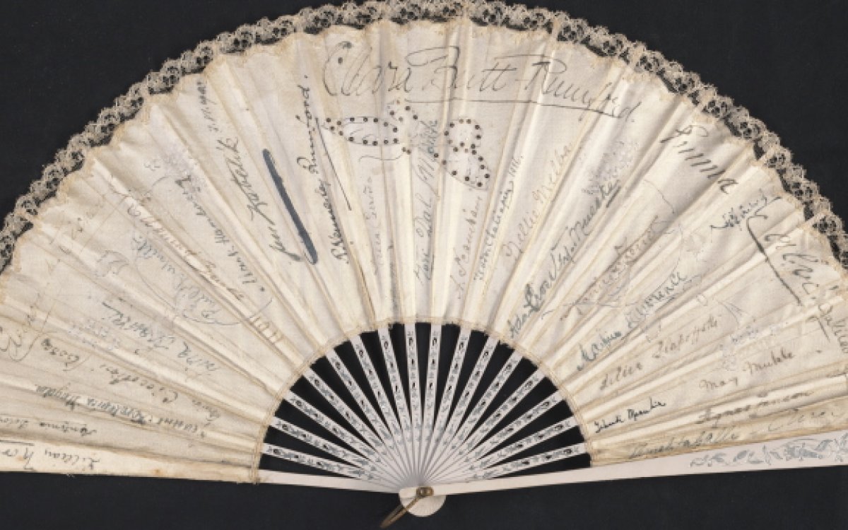 An open commemorative fan with signatures.