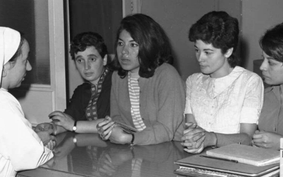 Social worker Sister Margherita speaking to four young South American migrant women over a counter at the Catholic Family Welfare Bureau in Sydney