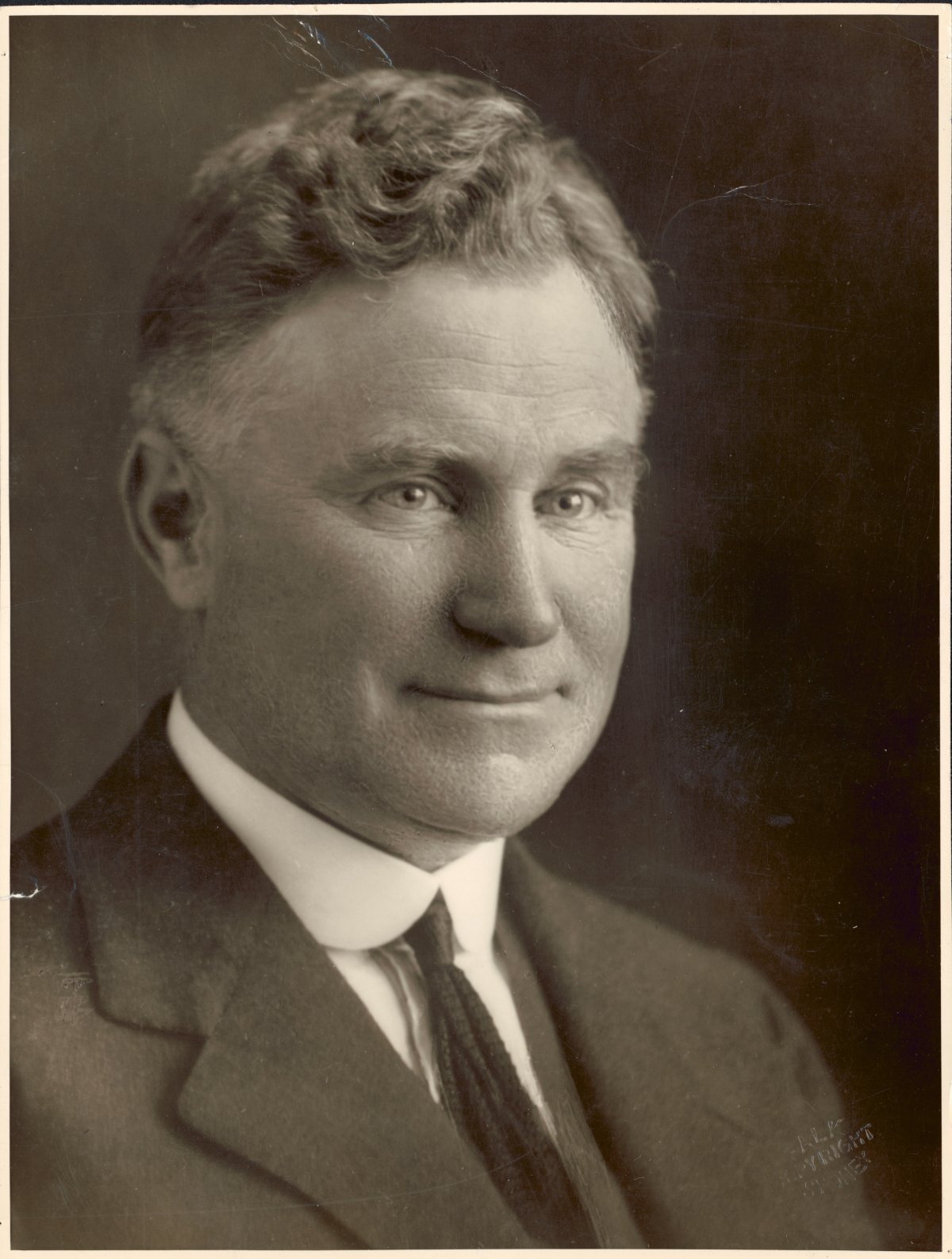 A formal portrait of Sir Earle Page, leader of the Country Party in 1939. He is a middle-aged white male with blonde wavy hair neatly groomed. He is wearing a light coloured suit with a dark tie and white shirt. He stares off camera