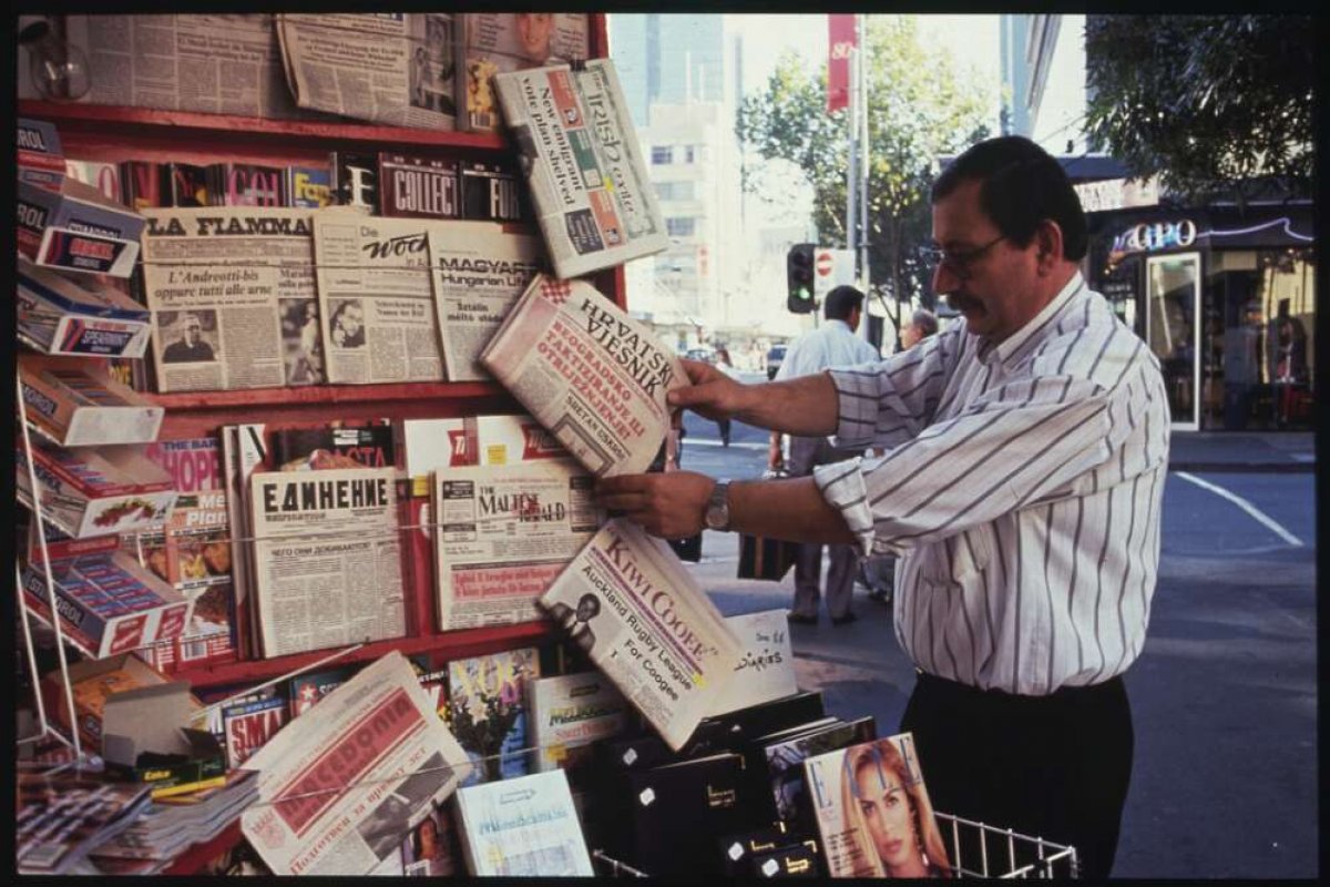 A man looking at newspapers in multiple languages at a newspaper kiosk on Elizabeth Street, Melbourne.