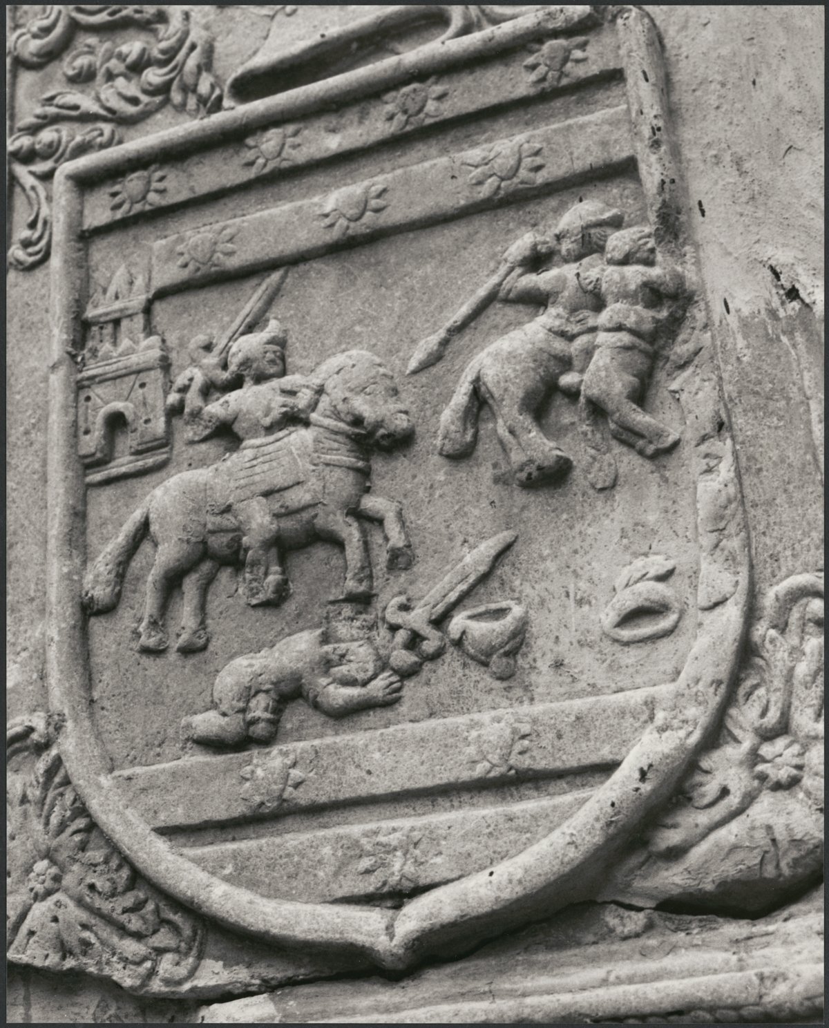 A close up of an architectural detail on a building. The detail is a knight on horseback fighting. The image is enclosed in a shield.