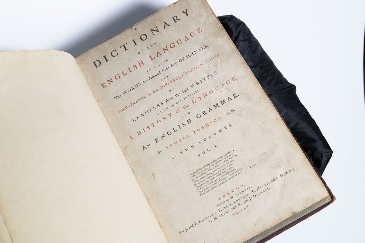 A rare old book opened to the title page. 'Dictionary' is on the top of the page with 'English Language' in red underneath. Other words are displayed below this text. 