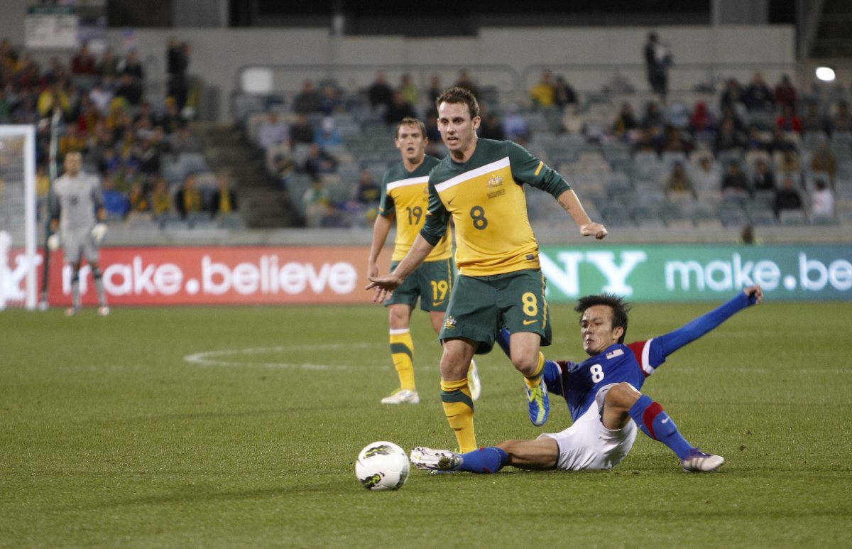 Photo of a Socceroos player being tackled by a Malaysian player