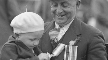 Child playing with the medals of a returned soldier at the ANZAC Day service at Petersham, New South Wales, 25 April 1933