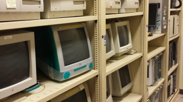 Old fashioned computers and other machines sit on tall beige shelves