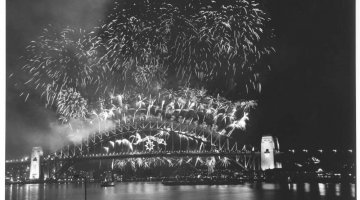 Black and white photograph of a fireworks display over Sydney Harbor Bridge