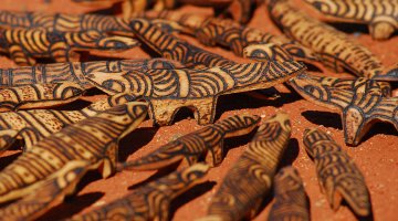 Carved wooden objects arranged on red sand