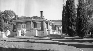 Black and white photograph of a house set in lush gardens